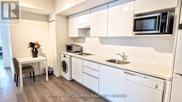 Waterloo condo for rent - A kitchen with white cabinets and appliances, a sink, a microwave, and a dishwasher.