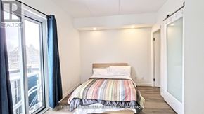Waterloo condo for rent - A bedroom with a striped bedspread and a large window.