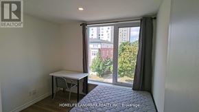 Waterloo condo for rent - A room with a table and a window showing a view of a building and trees.