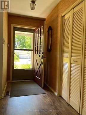 London North (North H) apartment for rent - A hallway with a wooden floor, a brown door, and a mirror on the wall.