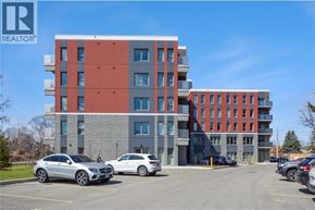 Hamilton condo for rent - A modern multi-story building with a parking lot in front.
