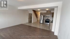 Zorra (Thamesford) townhouse for rent - A spacious room with wooden flooring and a staircase leading to another level.