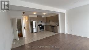 Zorra (Thamesford) townhouse for rent - A spacious, empty room with a kitchen area in the background.
