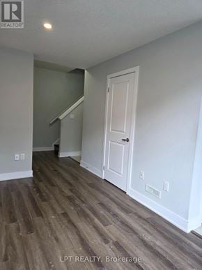 London East (East D) townhouse for rent - A room with a white door and a staircase in the background.