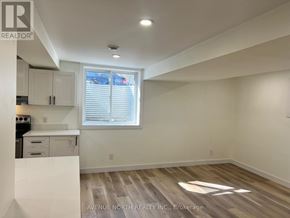 Ottawa apartment for rent - A real estate listing photo of a white kitchen with wood flooring and a window.