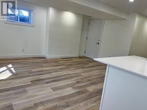 Ottawa apartment for rent - A room with wooden flooring and white walls, with a door and a window.