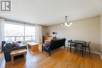 Toronto (East End-Danforth) apartment for rent - A living room with a black couch, a wooden coffee table, and a dining table with chairs.