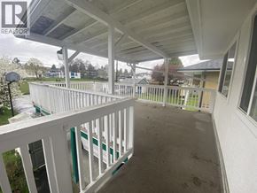 Burnaby apartment for rent - A white porch with a green railing and a white house in the background.