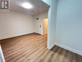 Toronto (South Riverdale) apartment for rent - A room with wooden flooring and white walls, with a door on the right side.