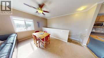 Grande Prairie apartment for rent - A living room with a black leather couch and a wooden dining table.