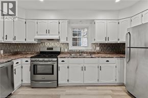Welland apartment for rent - A kitchen with white cabinets and a black stove top oven.