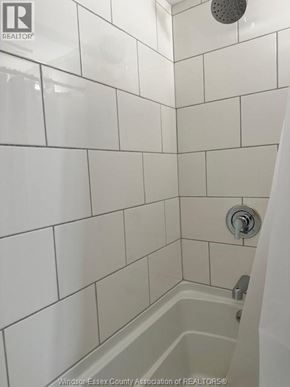 Belle River apartment for rent - A white tiled shower with a shower head and a faucet.