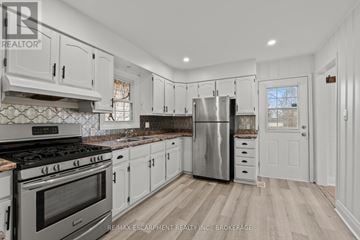 Welland (Prince Charles) multi-family for rent - A kitchen with white cabinets and a stainless steel refrigerator.