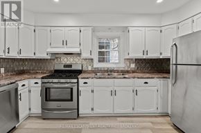 Welland (Prince Charles) multi-family for rent - A kitchen with white cabinets and a stove top oven.
