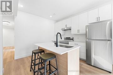 London South (South F) multi-family for rent - A kitchen with white cabinets and a white island with a sink.