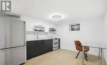 Toronto (Wexford-Maryvale) apartment for rent - A kitchen with a refrigerator, a microwave, and a table with a chair.