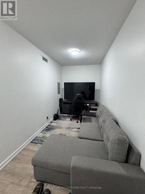 Toronto (Woodbine Corridor) condo for rent - A room with a grey couch and a television on the wall.