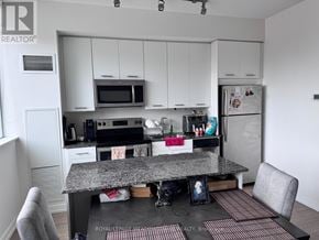 Toronto (Woodbine Corridor) condo for rent - A kitchen with white cabinets and a granite countertop.
