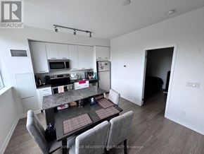 Toronto (Woodbine Corridor) condo for rent - A kitchen with a table and chairs in the foreground and a refrigerator, microwave, and oven in the background.