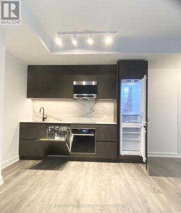 Toronto (Mount Pleasant East) condo for rent - A modern kitchen with dark brown cabinets and stainless steel appliances.