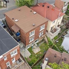 Ottawa apartment for rent - A red brick building with a brown roof is surrounded by other buildings.