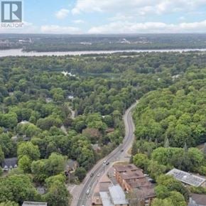 Ottawa apartment for rent - A road meanders through a wooded area with a building on the right.