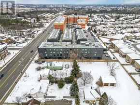 Oshawa (Samac) condo for rent - A large building with a grey and orange exterior sits in the middle of a snowy residential area.