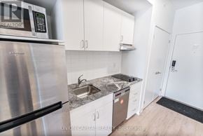 Oshawa (Samac) condo for rent - A kitchen with a stainless steel refrigerator and a granite countertop.