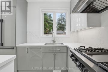 Mississauga (Port Credit) apartment for rent - A modern kitchen with a stainless steel stove and white cabinets.