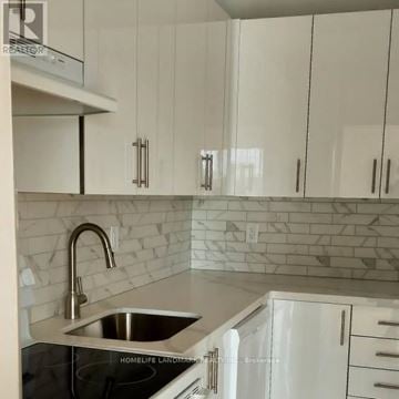 Mississauga (Cooksville) multi-family for rent - A kitchen with white cabinets and a marble backsplash.