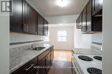Burlington (Brant) condo for rent - A kitchen with dark wood cabinets and a white stove top oven.