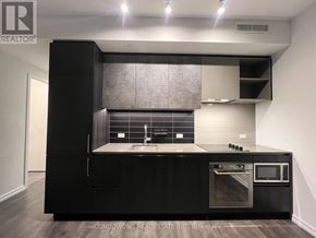 Vaughan (Vaughan Corporate Centre) condo for rent - A modern kitchen with black cabinets and stainless steel appliances.