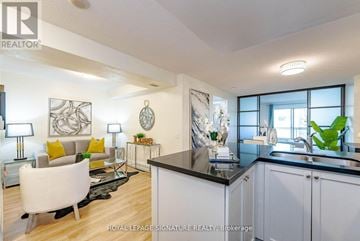 Toronto (Willowdale East) condo for rent - A well-lit, modern kitchen and living room with white furniture and a black countertop.