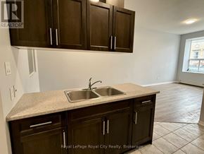 Guelph (Downtown) multi-family for rent - A kitchen with brown cabinets and a granite countertop.