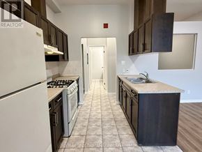 Guelph (Downtown) multi-family for rent - A kitchen with white appliances and dark wood cabinets.