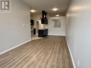 Guelph (Downtown) multi-family for rent - A spacious room with wooden flooring and white walls.