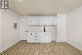 Toronto (Kensington-Chinatown) condo for rent - A white kitchen with wooden floors and cabinets.