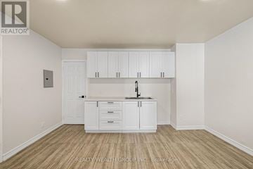 Toronto (Kensington-Chinatown) condo for rent - A white kitchen with wooden floors and cabinets.