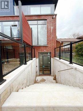 Toronto (Bathurst Manor) apartment for rent - A red brick house with a glass door and a staircase leading to it.