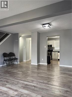 Waterloo townhouse for rent - A room with a wooden floor and a kitchen in the background.