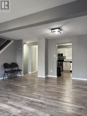 Waterloo townhouse for rent - A room with a wooden floor and a kitchen in the background.