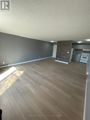 Welland (Lincoln/Crowland) multi-family for rent - A room with wooden flooring and a kitchen area in the background.