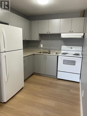 Welland (Lincoln/Crowland) multi-family for rent - A white refrigerator is in a kitchen with wooden floors and white appliances.