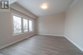 Thorold (Hurricane/Merrittville) apartment for rent - A spacious room with a large window and wooden flooring.