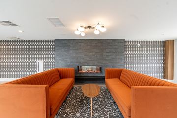 Columbus apartment for rent - A modern living room with orange couches and a fireplace.