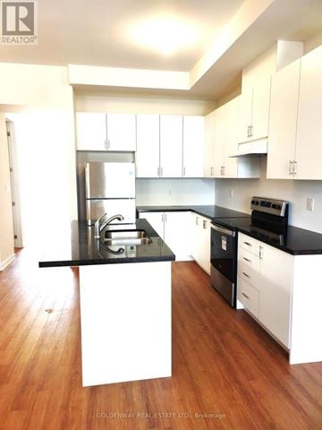 Markham (Wismer) townhouse for rent - A kitchen with white cabinets and black countertops.