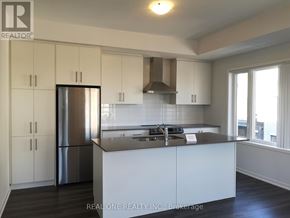 Toronto (New Toronto) townhouse for rent - A kitchen with white cabinets and a stainless steel refrigerator.