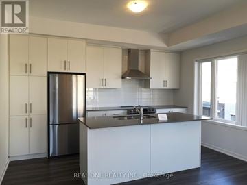 Toronto (New Toronto) townhouse for rent - A kitchen with white cabinets and a stainless steel refrigerator.