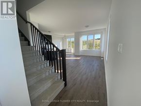 Kitchener townhouse for rent - A staircase with a black railing leads to a bright room with a large window.