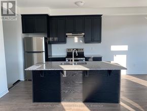 Kitchener townhouse for rent - A kitchen with black cabinets and a stainless steel refrigerator.
